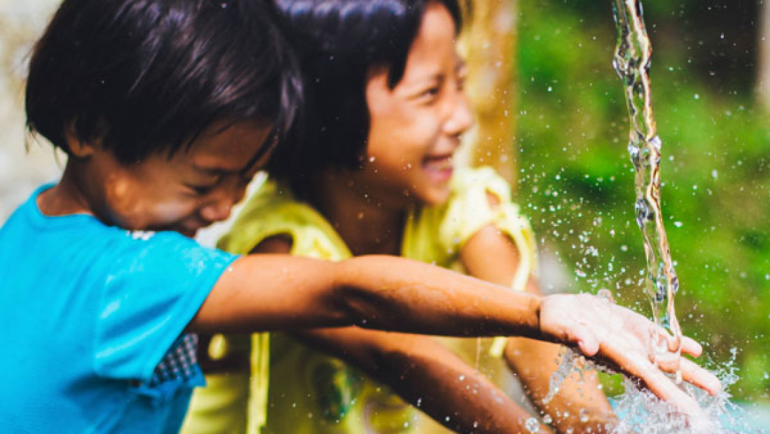 Two kids playing in a fountain